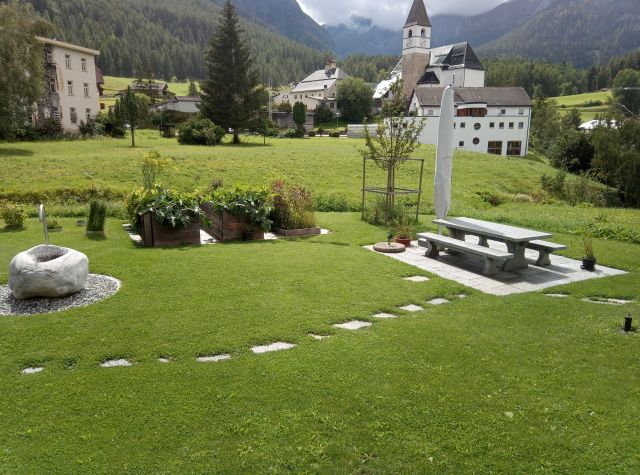 Gartenanlage in Tarasp im Engadin Gartenanlage aus Steintisch, Steinbrunnen, Hochbeet und grüner Wiese in Tarasp im Engadin.